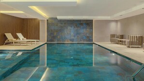 A modern indoor swimming pool with lounge chairs and a stone wall. - Le Méridien Casablanca (Casablanca)