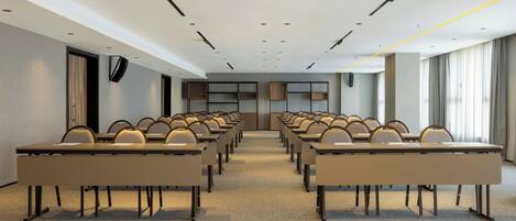 A conference room with rows of tables and chairs, a neutral color scheme, and a modern design.
