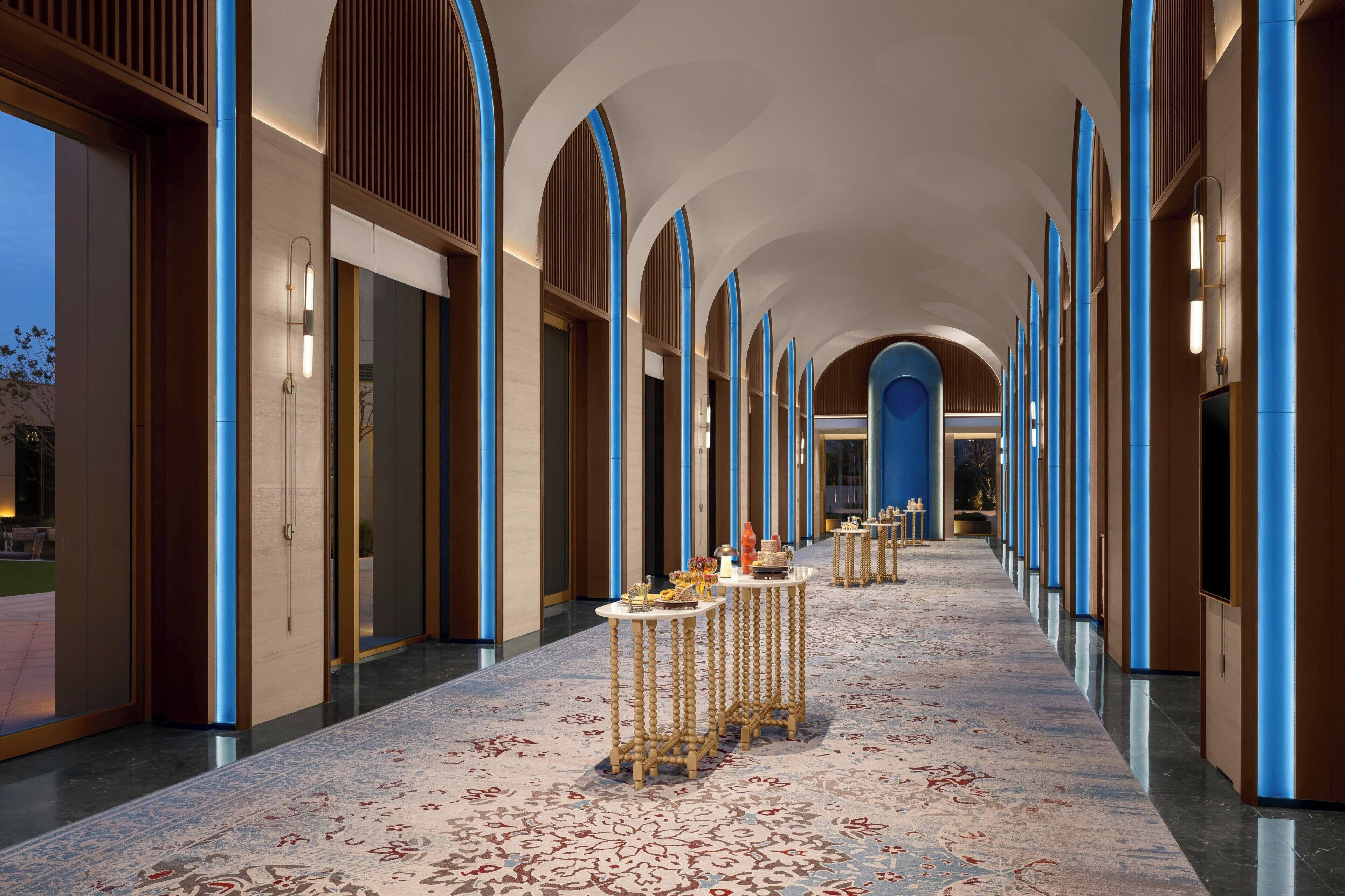 A hotel corridor with arched ceilings, wooden paneling, and a patterned carpet.