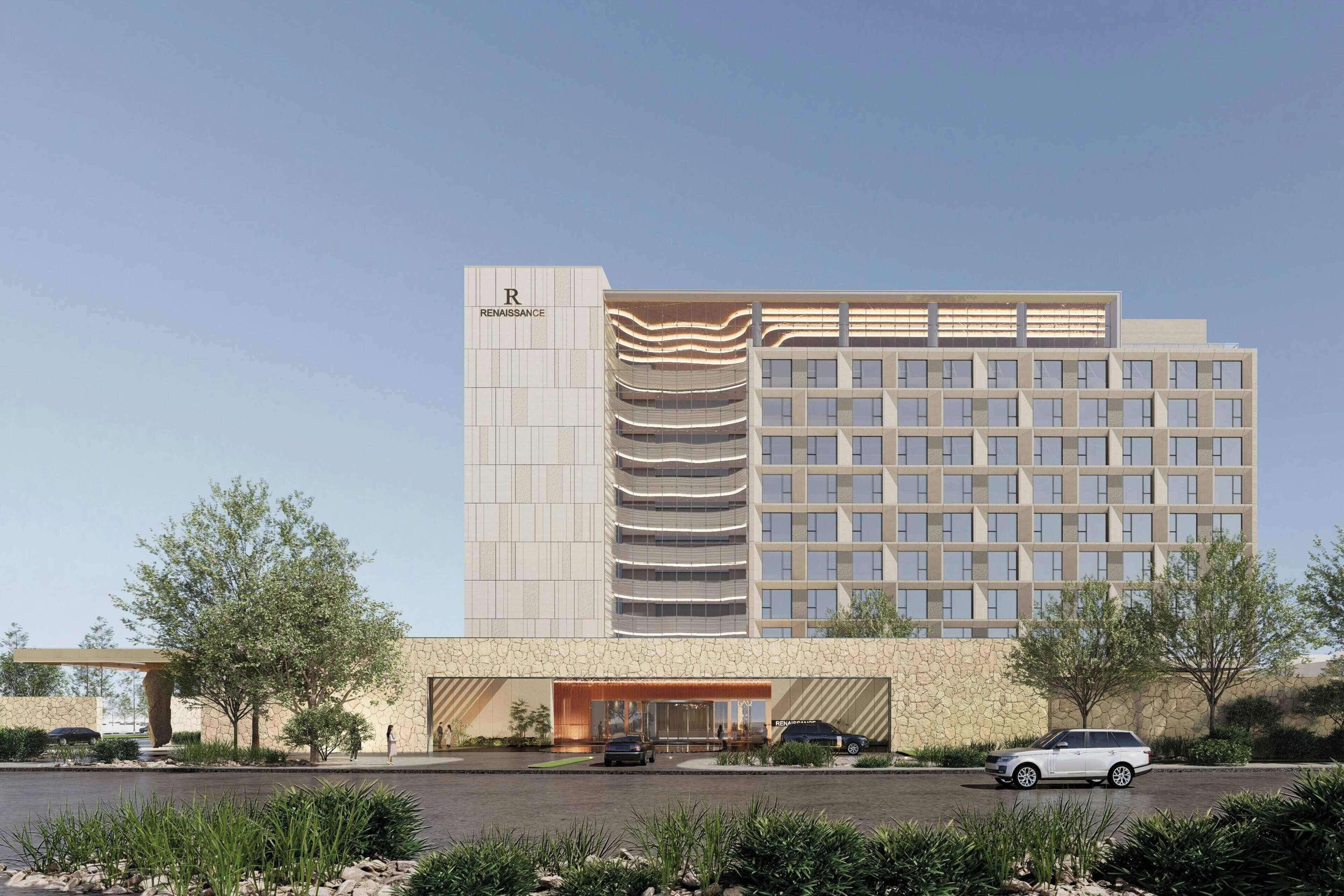 A modern hotel with a prominent 'Renaissance' sign, a multi-story structure, and a parking area with cars.