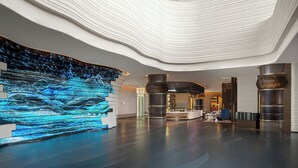 A spacious lobby with a modern design, featuring a large digital waterfall display, a reception desk, and a seating area. - Renaissance Korla Hotel (Korla)