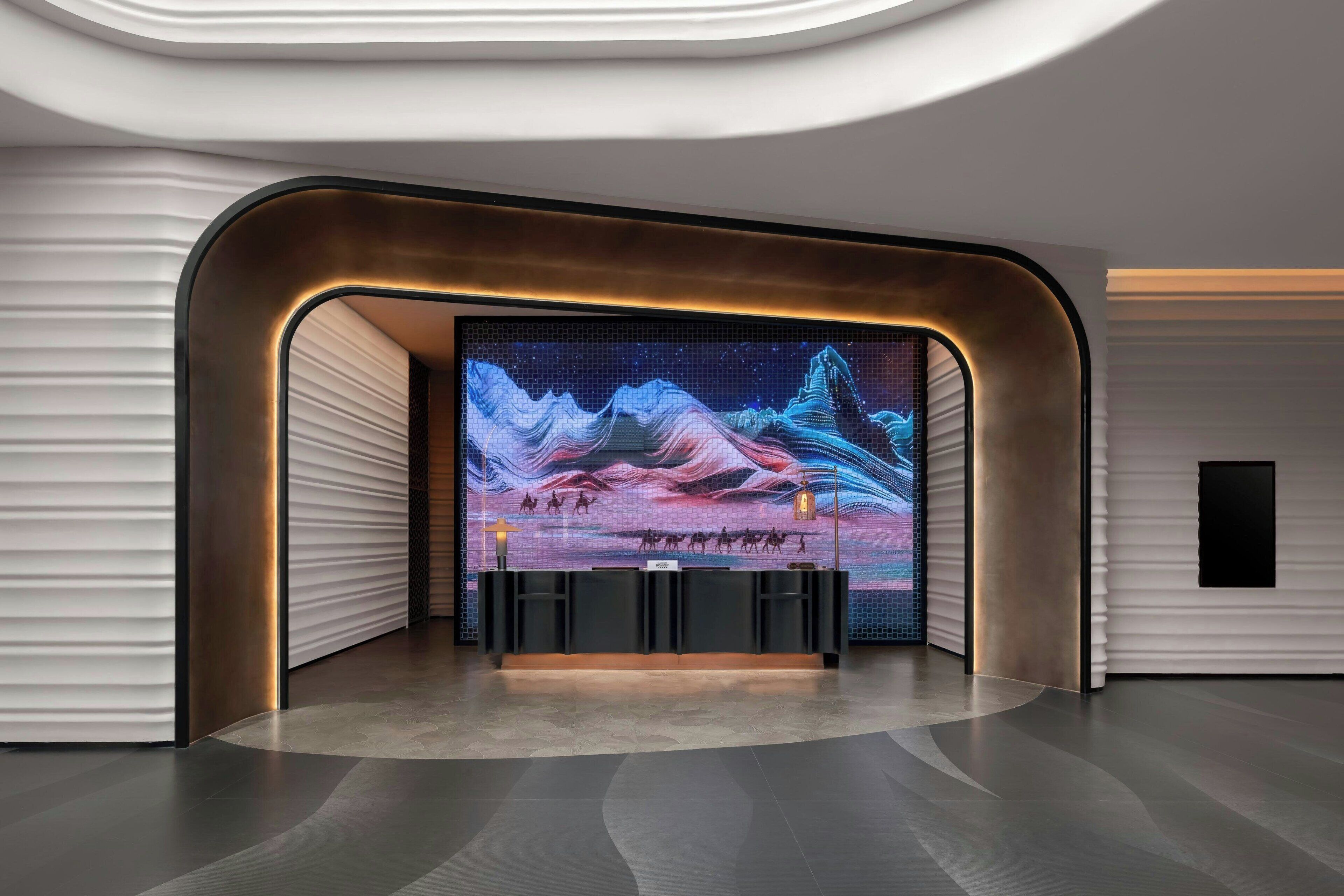 A modern reception area with a large digital display, sleek black reception desk, and a minimalist design.
