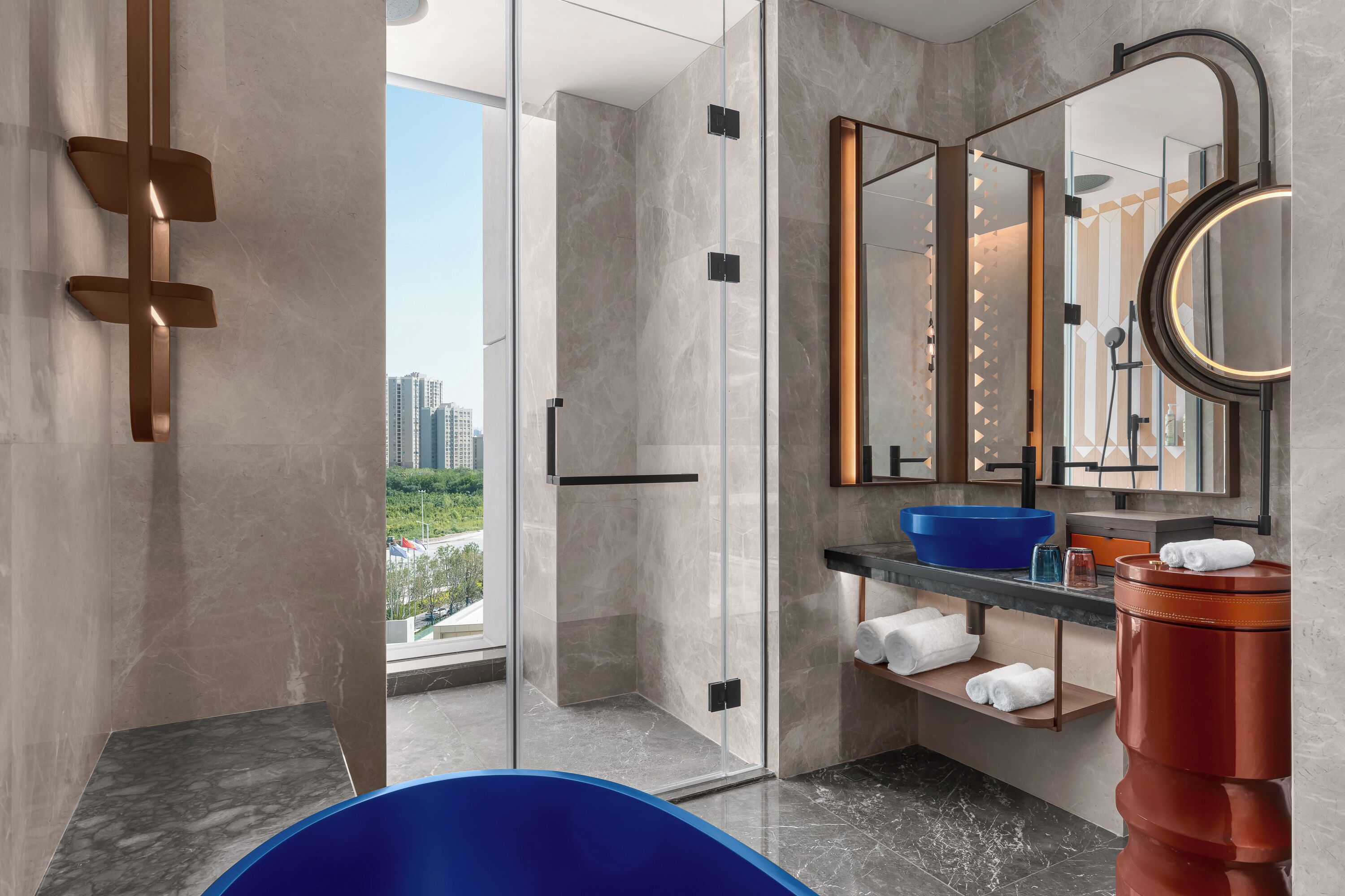 Un bagno moderno con cabina doccia in vetro, lavabo blu e un ampio specchio.