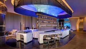 A modern bar area with a curved ceiling and a large screen displaying a blue sky. - Renaissance Korla Hotel (Korla)