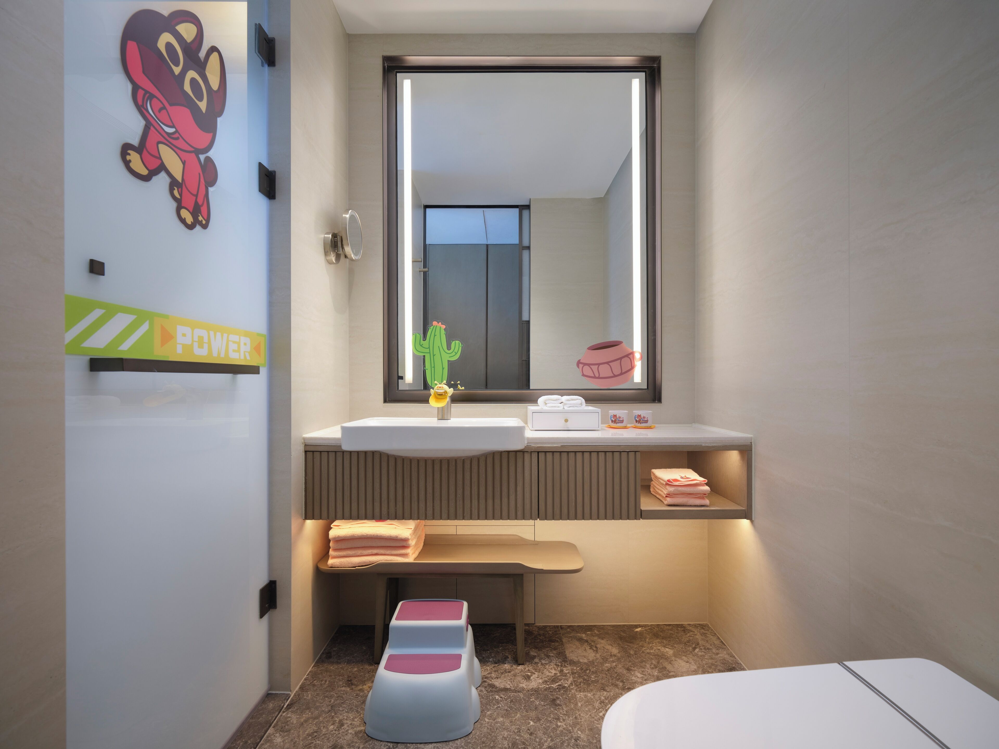 Un baño moderno con un espejo grande, un lavamanos, un banco y un inodoro.