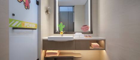 Un baño moderno con un espejo grande, un lavamanos, un banco y un inodoro.