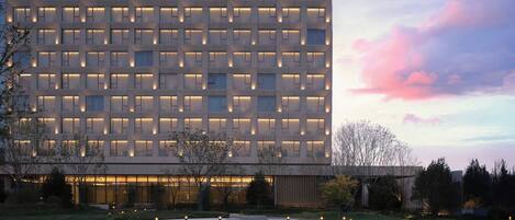 A modern building with a grid of windows and a landscaped courtyard with pathways and lights.