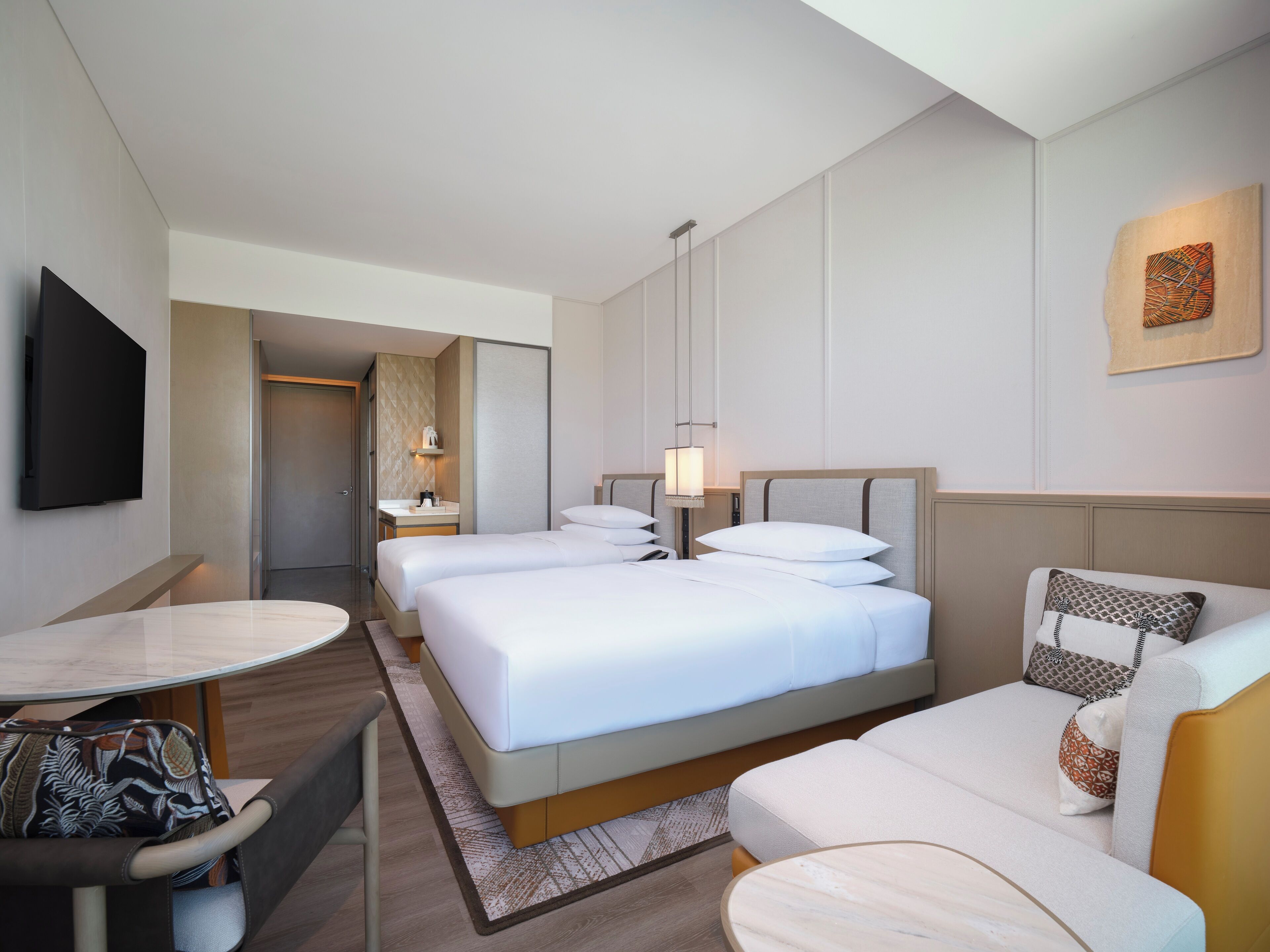 A hotel room with a bed, a sofa, a desk, and a TV.