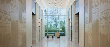 A modern hallway with patterned walls, a bench, and a large window with a view of trees.