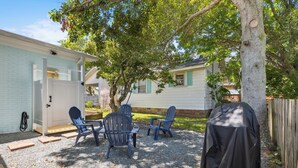 A backyard with a covered grill, a covered chair, and a covered table. - Rec Player's Retreat by Carolina Retreats (Carolina Beach)
