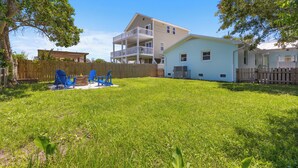A two-story house with a fenced backyard, a wooden deck, and a small shed. - Rec Player's Retreat by Carolina Retreats (Carolina Beach)