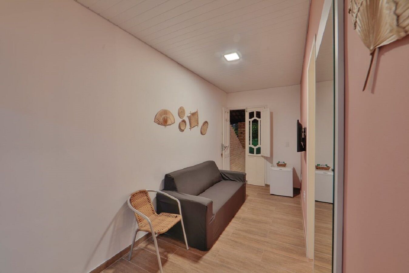 A room with a sofa, a wicker chair, and a small table. There is a door leading to a staircase.