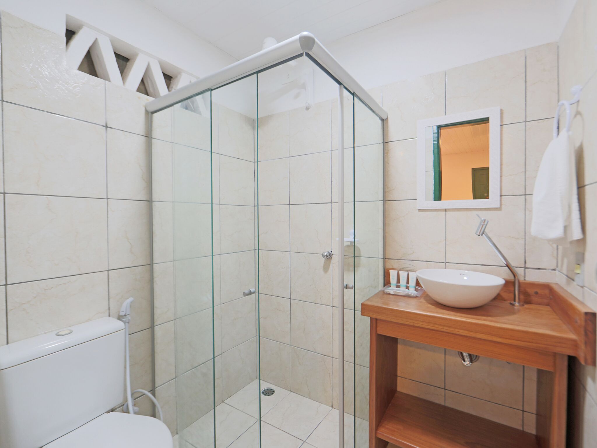Une salle de bain moderne avec une douche à parois de verre, des toilettes blanches et un meuble-lavabo en bois avec un évier.