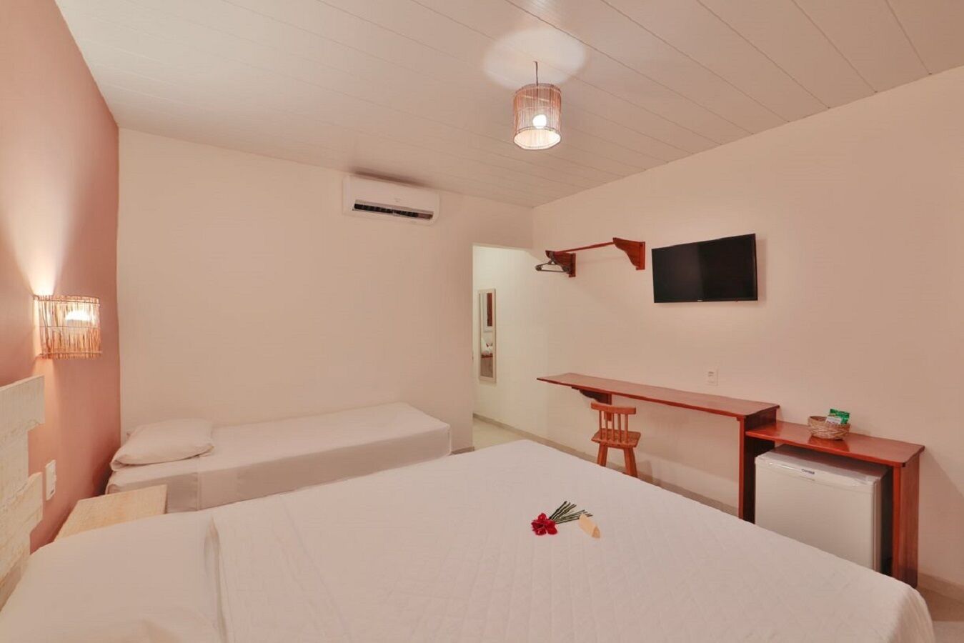 A hotel room with two single beds, a desk, a television, and a small refrigerator.