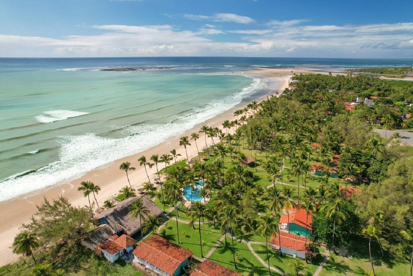 A coastal resort with beachfront properties, palm trees, and a swimming pool.