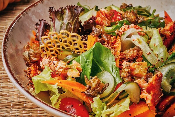Un tazón de ensalada mixta con diversos vegetales y mariscos.