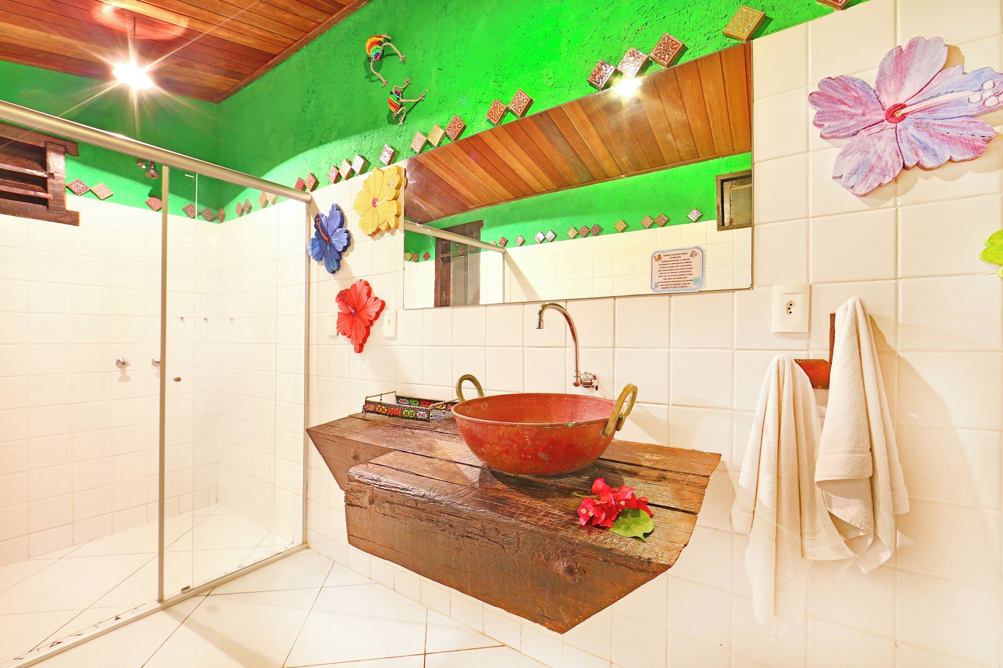 Een badkamer met een douchecabine van glas, een houten wastafelmeubel met een grote waskom en een spiegel boven de wastafel.