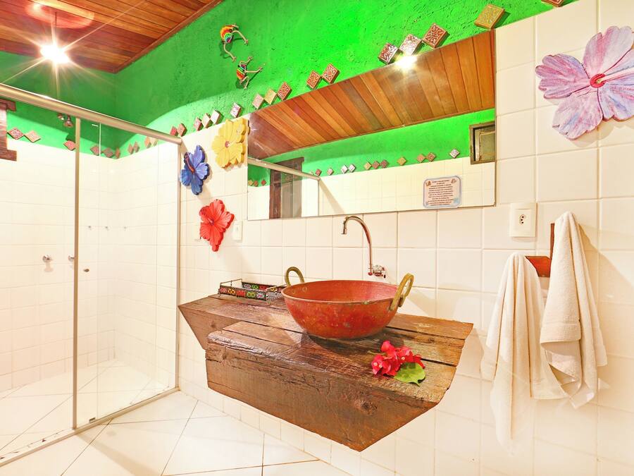 Een badkamer met een douchecabine van glas, een houten wastafelmeubel met een grote waskom en een spiegel boven de wastafel.