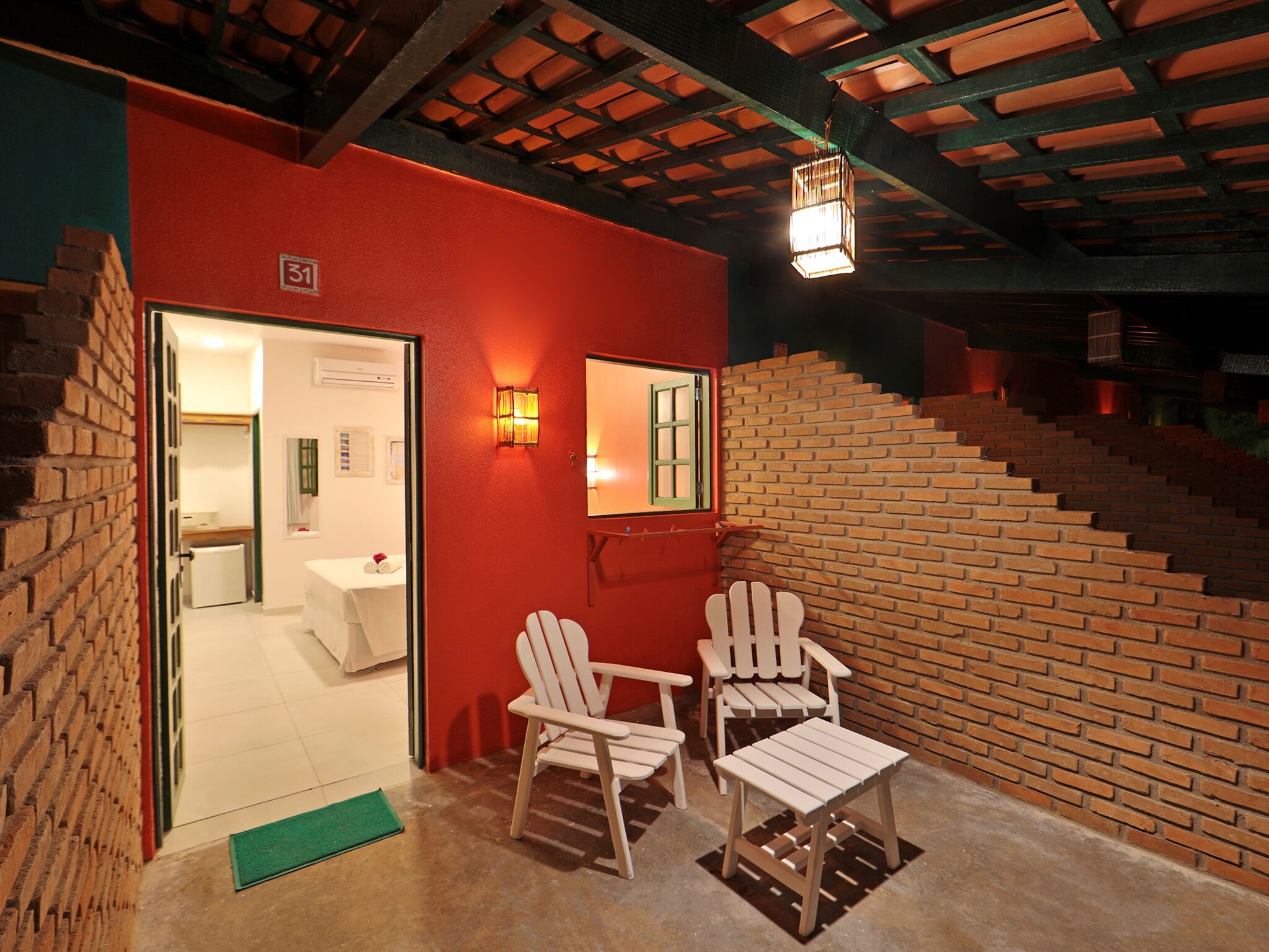 Ein Zimmer mit roter Wand, einer Holztreppe und zwei weißen Stühlen.