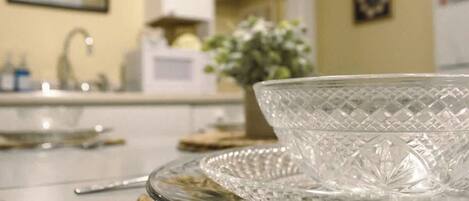 A kitchen with a clear glass bowl on a woven mat, a sink, and a microwave.