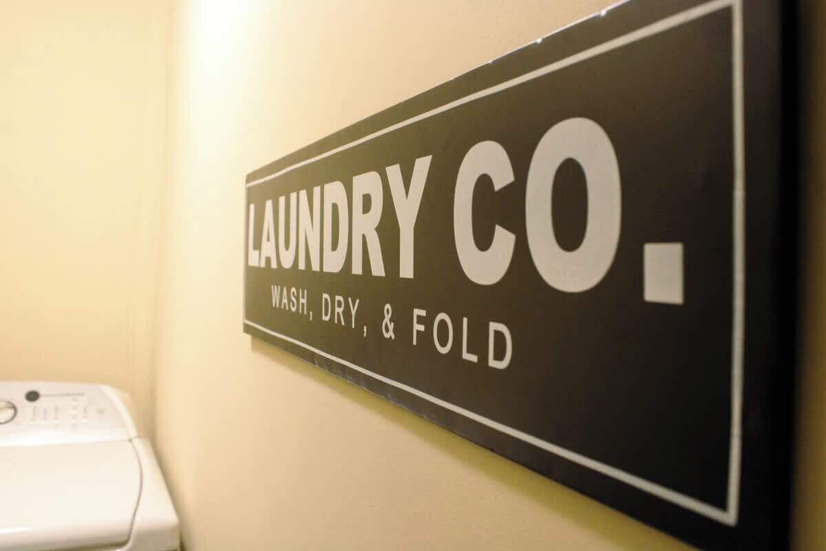 Letrero en la pared para un servicio de lavandería con la inscripción 'LAUNDRY CO. WASH, DRY, & FOLD'.