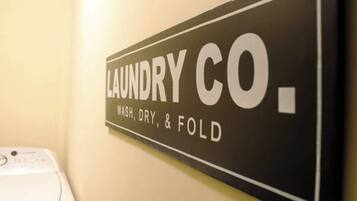 Letrero en la pared para un servicio de lavandería con la inscripción 'LAUNDRY CO. WASH, DRY, & FOLD'.