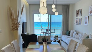 A modern living room with a dining area, a sofa, and a view of the ocean. - Seaview Paradise (Rethymno)