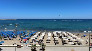 A beach with rows of sunbeds and umbrellas, a clear blue sky, and the ocean in the background. - Seaview Paradise (Rethymno)
