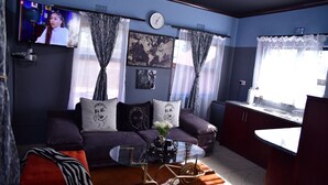 Ein modernes Wohnzimmer mit einer Couch, einem Glastisch und einem an der Wand befestigten Fernseher.