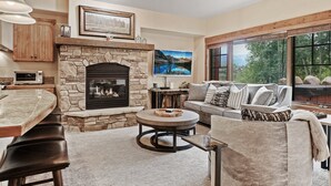 A cozy living room with a stone fireplace, a round coffee table, and a comfortable seating area with a sofa and armchairs.