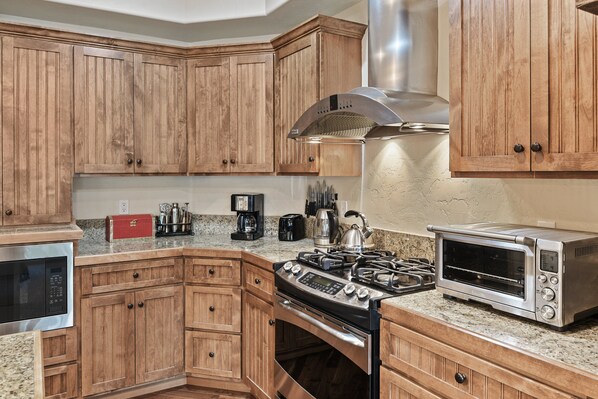 A kitchen with wooden cabinets, a gas stove, a built-in oven, a microwave, and a toaster.