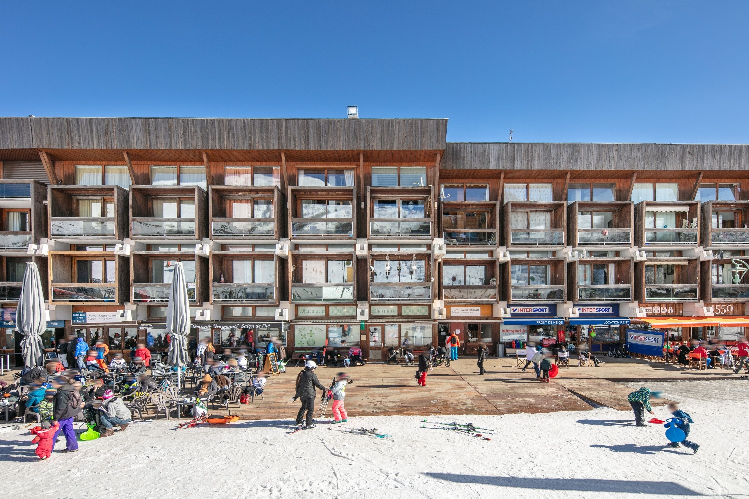 Een modern gebouw met meerdere balkons en een skipiste ervoor.