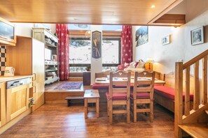 Een gezellige kamer met houten meubels, een eettafel en uitzicht op een piste.