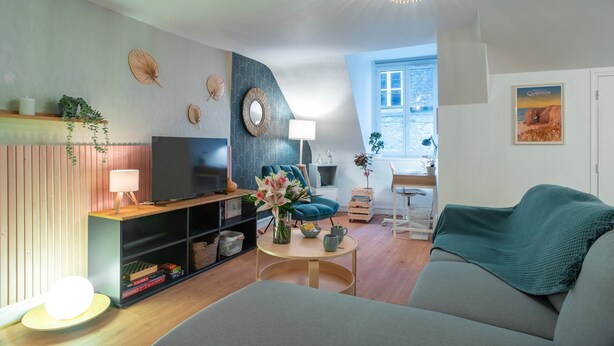 A modern living room with a flat-screen TV, a sofa, a coffee table, and decorative items.