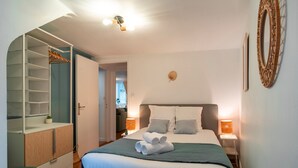 A bedroom with a bed, bedside tables, a wardrobe, and a mirror.