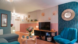 A modern living room with a sofa, a blue armchair, a TV, and a bookshelf.