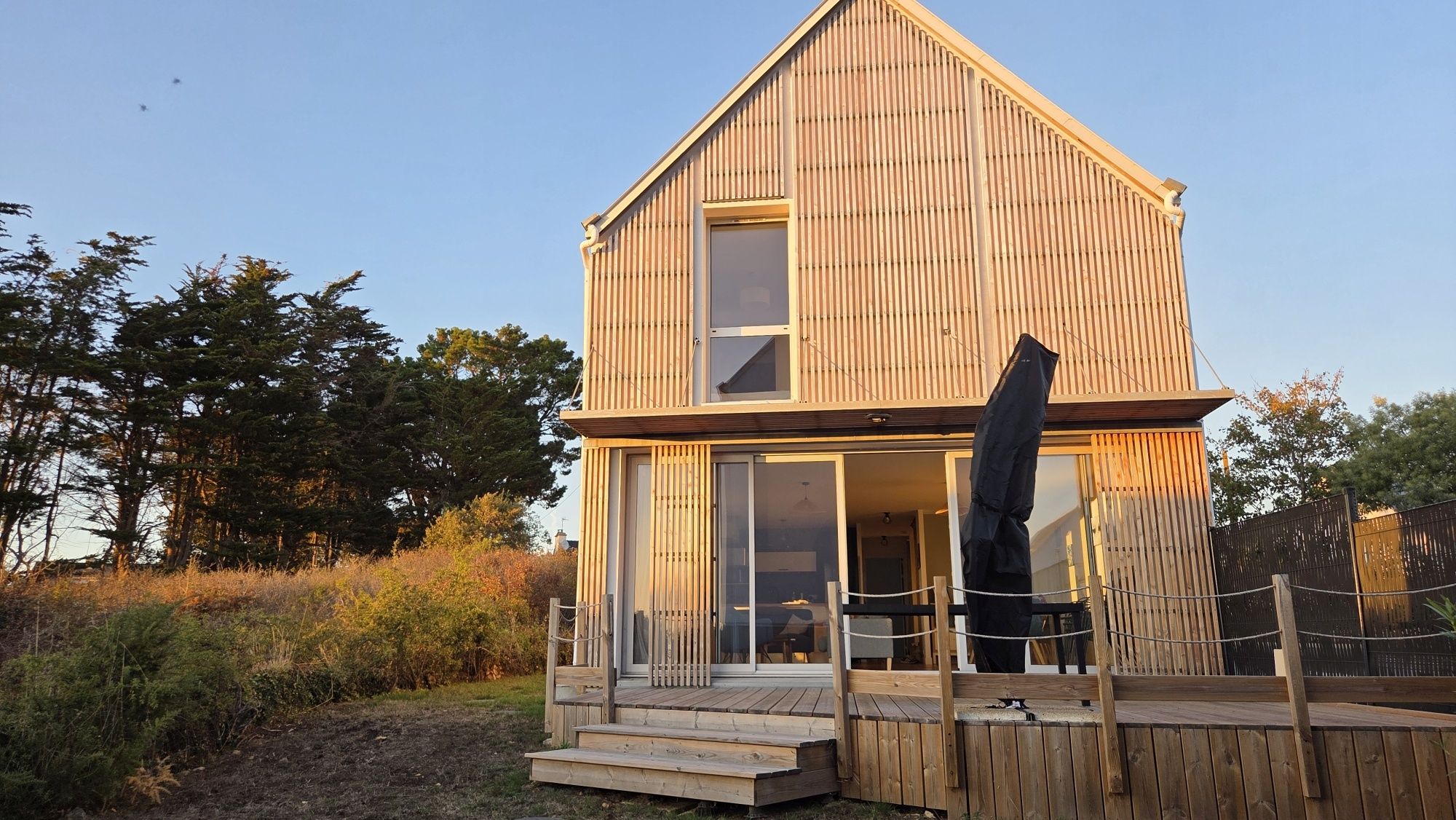 A two-story wooden house with a balcony and a large window.