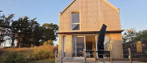 A two-story wooden house with a balcony and a large window.