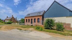 Een landelijke omgeving met een gebouw van baksteen, een grote blauwe constructie en een zandweg.