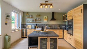 Een moderne keuken met houten kastjes, een centraal eiland en een zwart aanrecht.