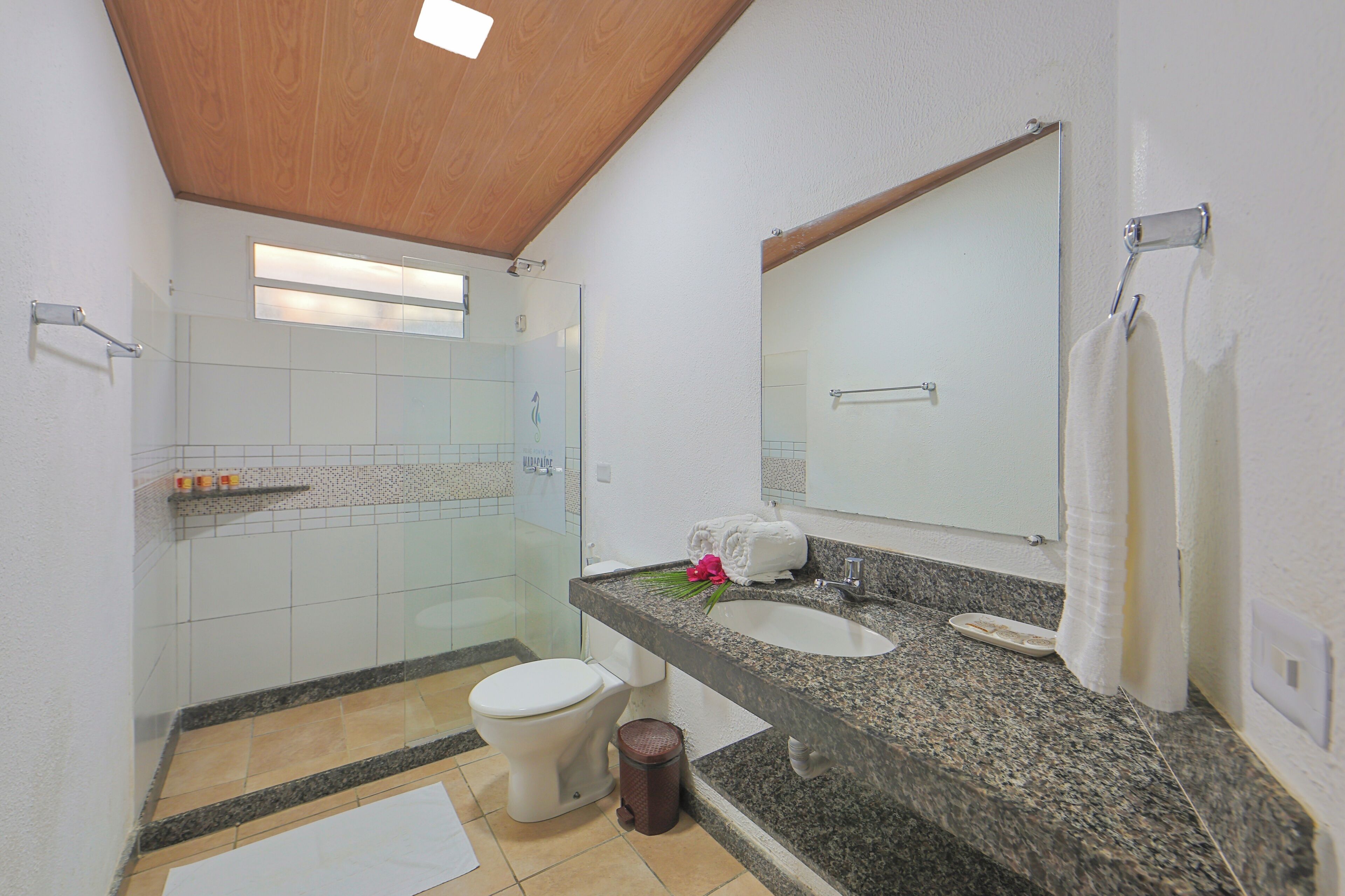 A bathroom with a toilet, sink, mirror, shower, and a towel rack.
