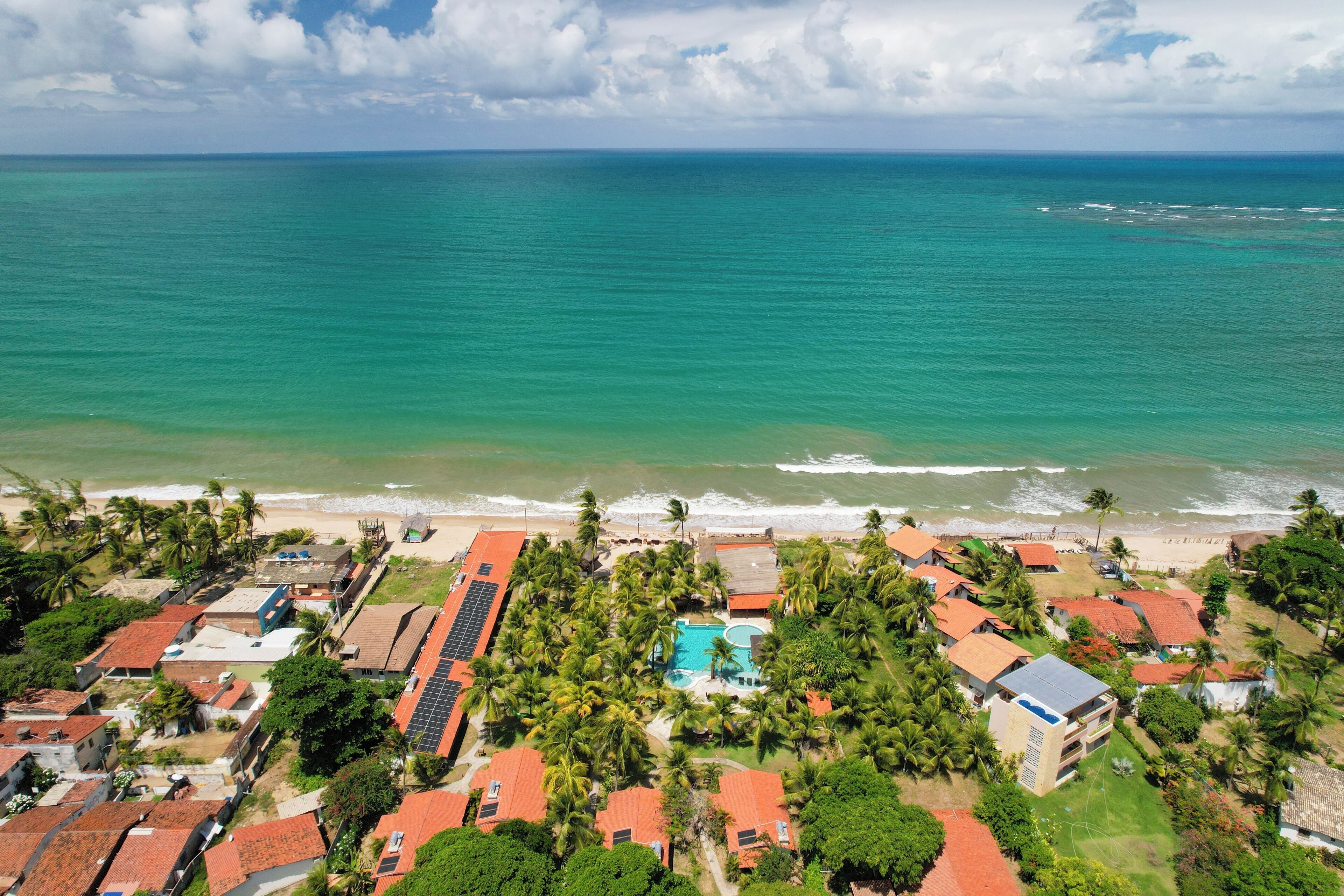 Vista aérea de una zona residencial costera con casas, piscina y playa.