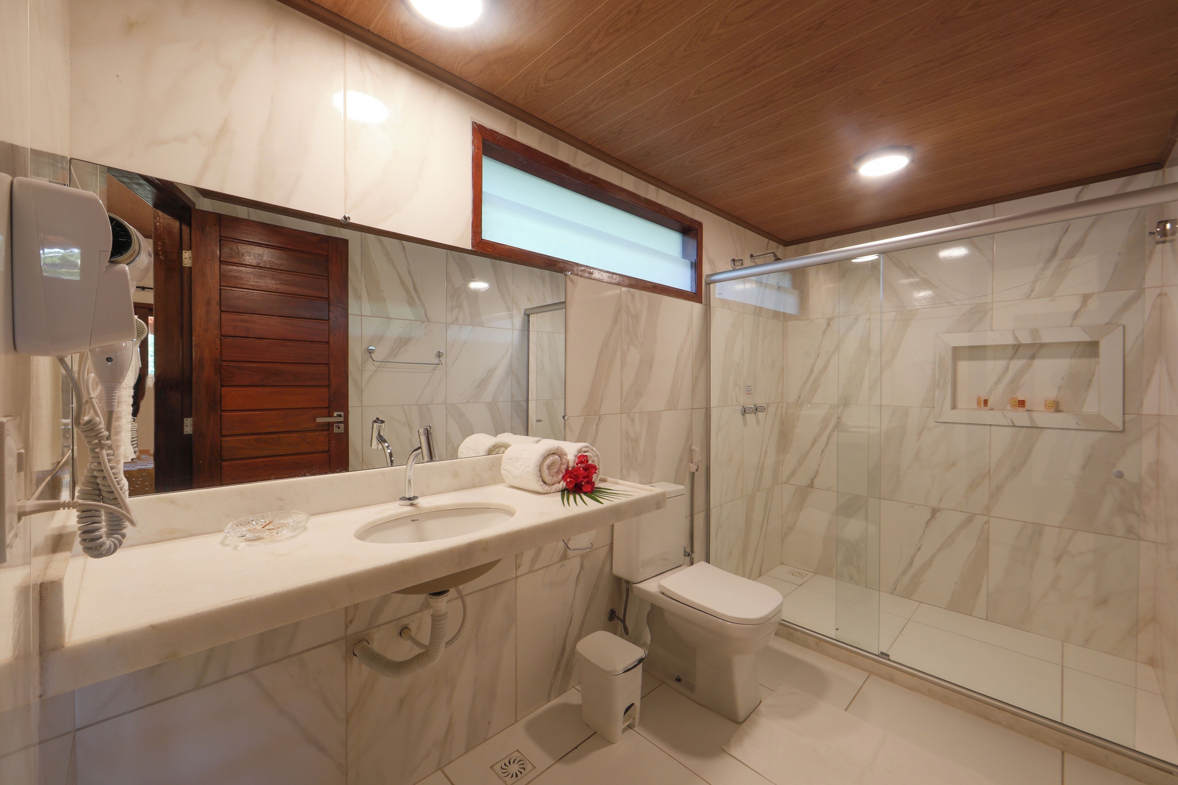 A modern bathroom with a marble sink, a toilet, and a glass shower enclosure.