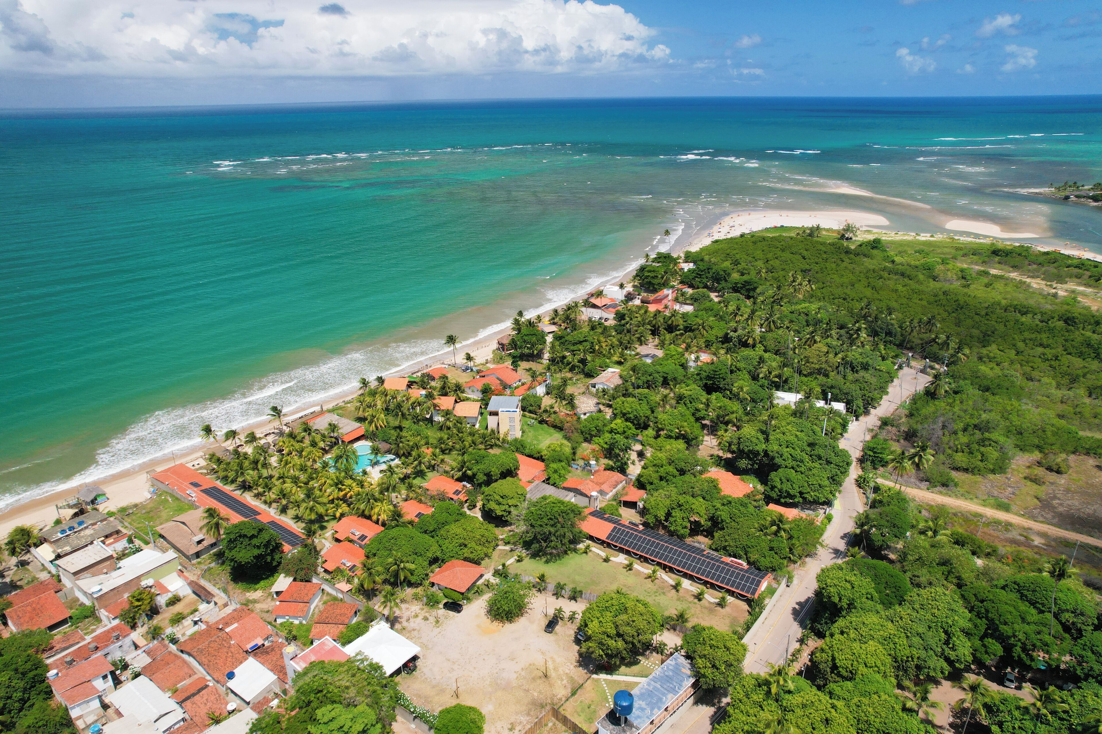 Vue aérienne d’une zone résidentielle côtière, avec des maisons, une plage et une vue dégagée sur l’océan.