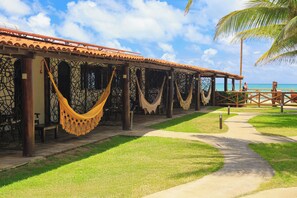A resort with a covered outdoor seating area, palm trees, and a pathway leading to the beach. - Pousada Privê Pontal  de Maracaípe (Ipojuca)