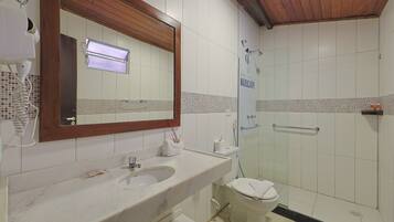 A bathroom with a marble sink, a toilet, a shower with a glass door, and a wooden ceiling.