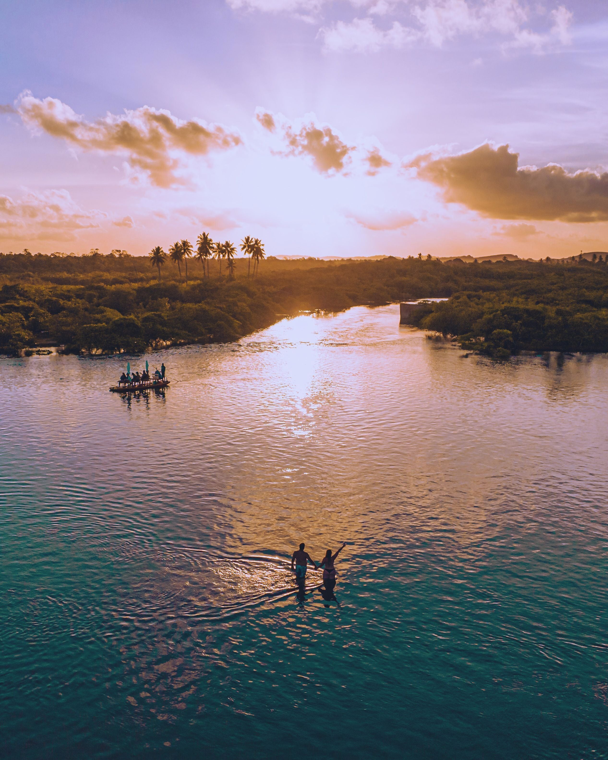 A river with clear water, a bridge in the background, and a boat with people.