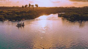 A river with clear water, a bridge in the background, and a boat with people.