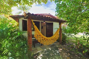 A small house with a hammock in front, surrounded by lush greenery.