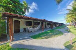 A building with a tiled roof, a hammock, and a pathway leading to a palm tree.